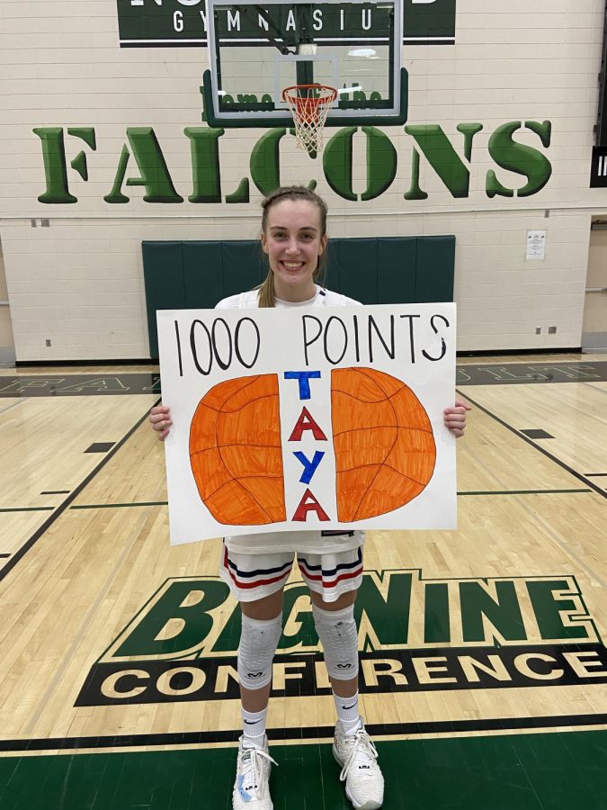 Jeffrey holds a sign made by one of her teammates after the game at Faribault High School. Many of her teammates and fans had created signs to commemorate her 1,000 point milestone. "She's the beast of the team," said Kendall Kenis, one of Jeffrey's teammates. 