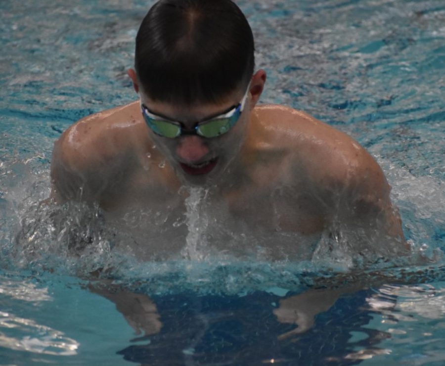 Junior Pacey Brekke warms up for the 100 meter breaststroke. He took first in the race.